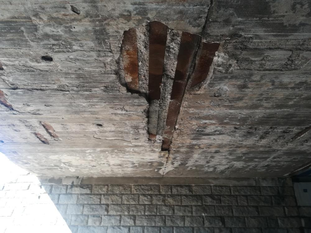 Olupující se beton ze stropu pod železničním mostem 