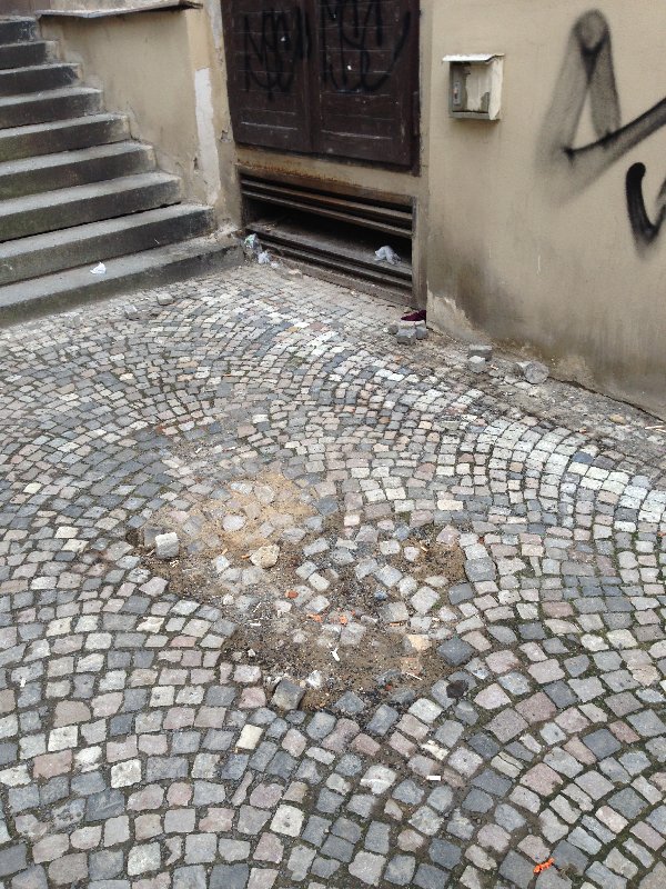 Díra v chodníku pod schody v ulici Chelčického