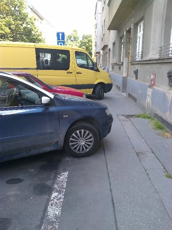 Parkující auta na chodníku.