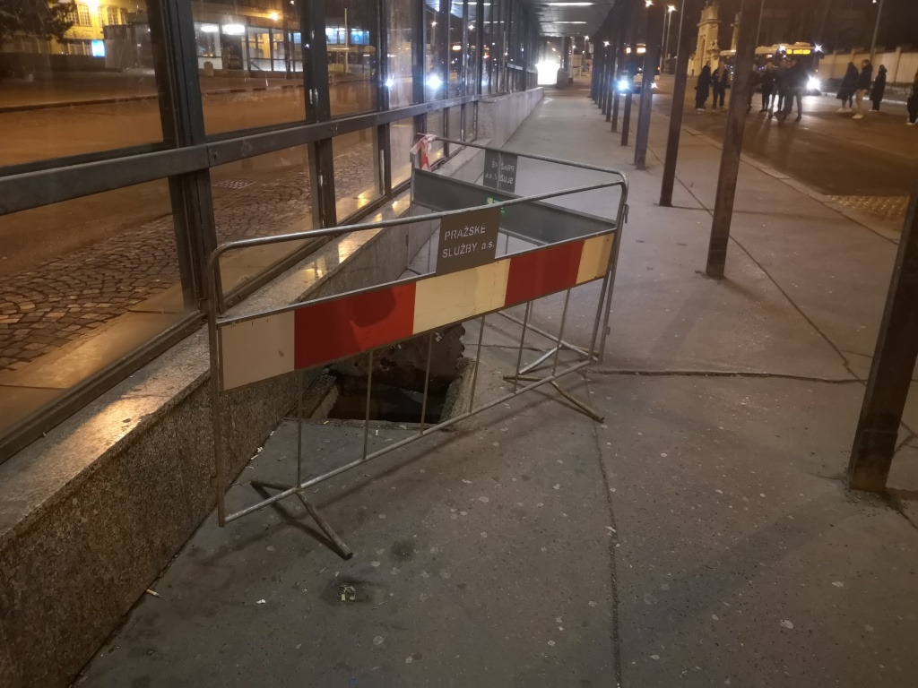 Rozpadlý poklop na autobusové zastávce Želivského